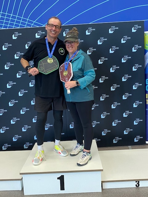 Player stretching at the net during an indoor pickleball match at Warrnambool 2026